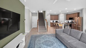 A modern living room with a flat-screen TV, a gray sofa, and a patterned rug.