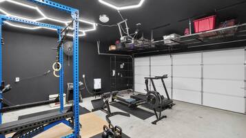Un gimnasio en casa con un rack de levantamiento de pesas azul, una bicicleta estática y una caminadora.