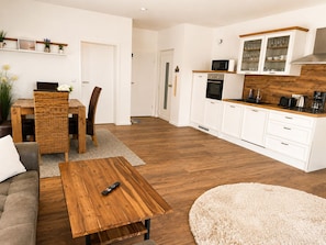A modern living room with a sofa, a wooden coffee table, and a TV. - Cozy vacation rental on Lake Hainer with 2 balconies and a lake view / 60 m² / sleeps 4 (Neukieritzsch)
