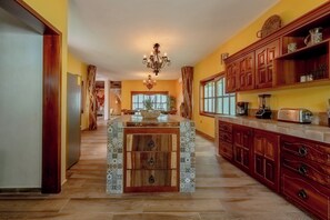 A kitchen with a central island, wooden cabinets, and a chandelier. - Villa Coral (Tulum)
