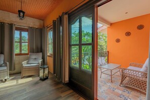 A room with a large sliding glass door leading to an outdoor balcony, wicker furniture, and a ceiling light fixture. - Villa Coral (Tulum)