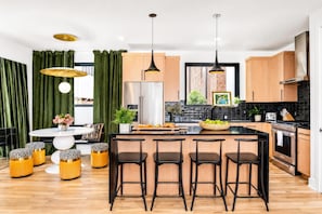 Eine moderne Küche mit Kochinsel, Barhocker und Essbereich mit rundem Tisch und Stühlen.