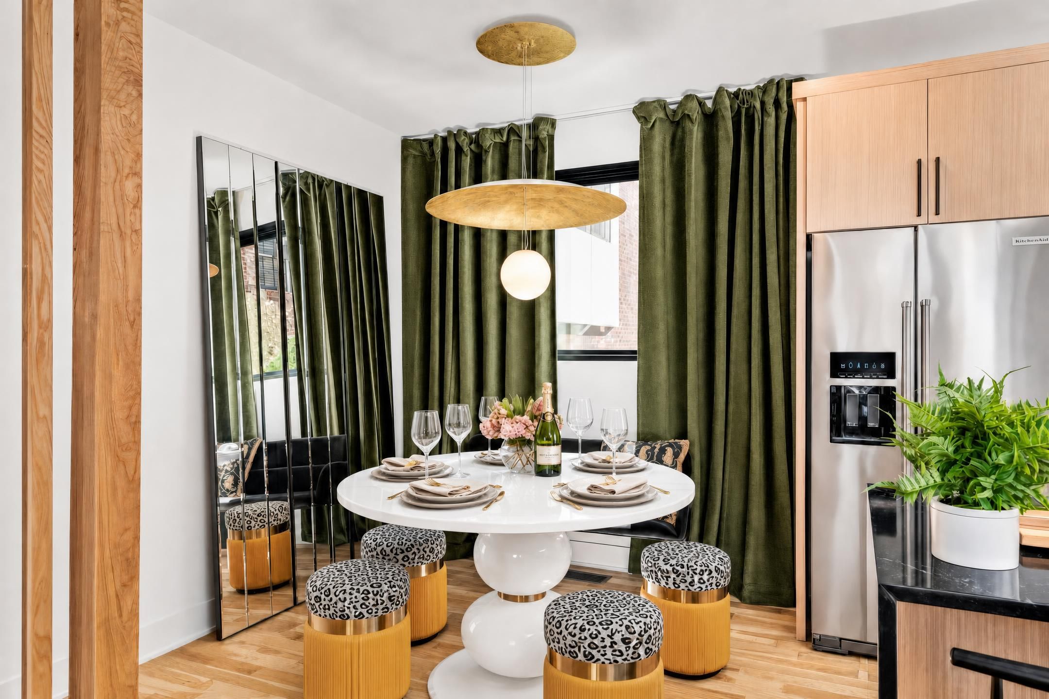 Een moderne keuken met een ingebouwde koelkast, een eethoek met een ronde tafel en groene gordijnen.