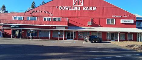 A red building with 'BOWLING BARN' signage, a storefront named 'ALLEY OOPS BISTRO,' and a car parked in front.