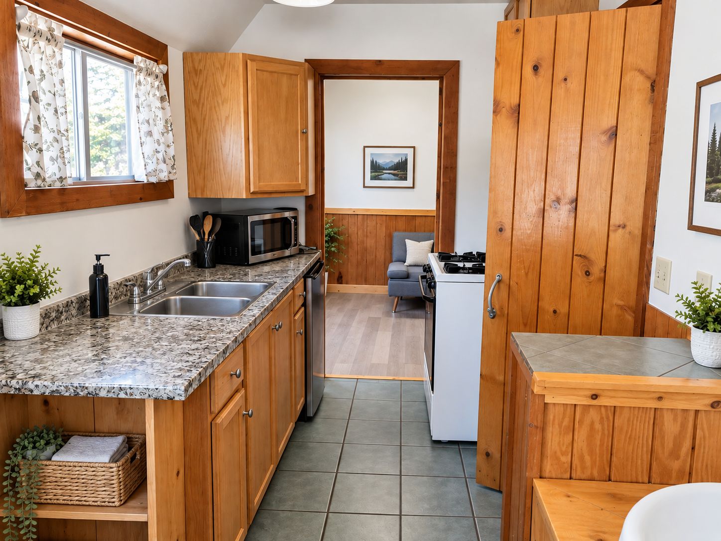 A compact kitchen with wooden cabinets, a microwave, a sink, and a stove.
