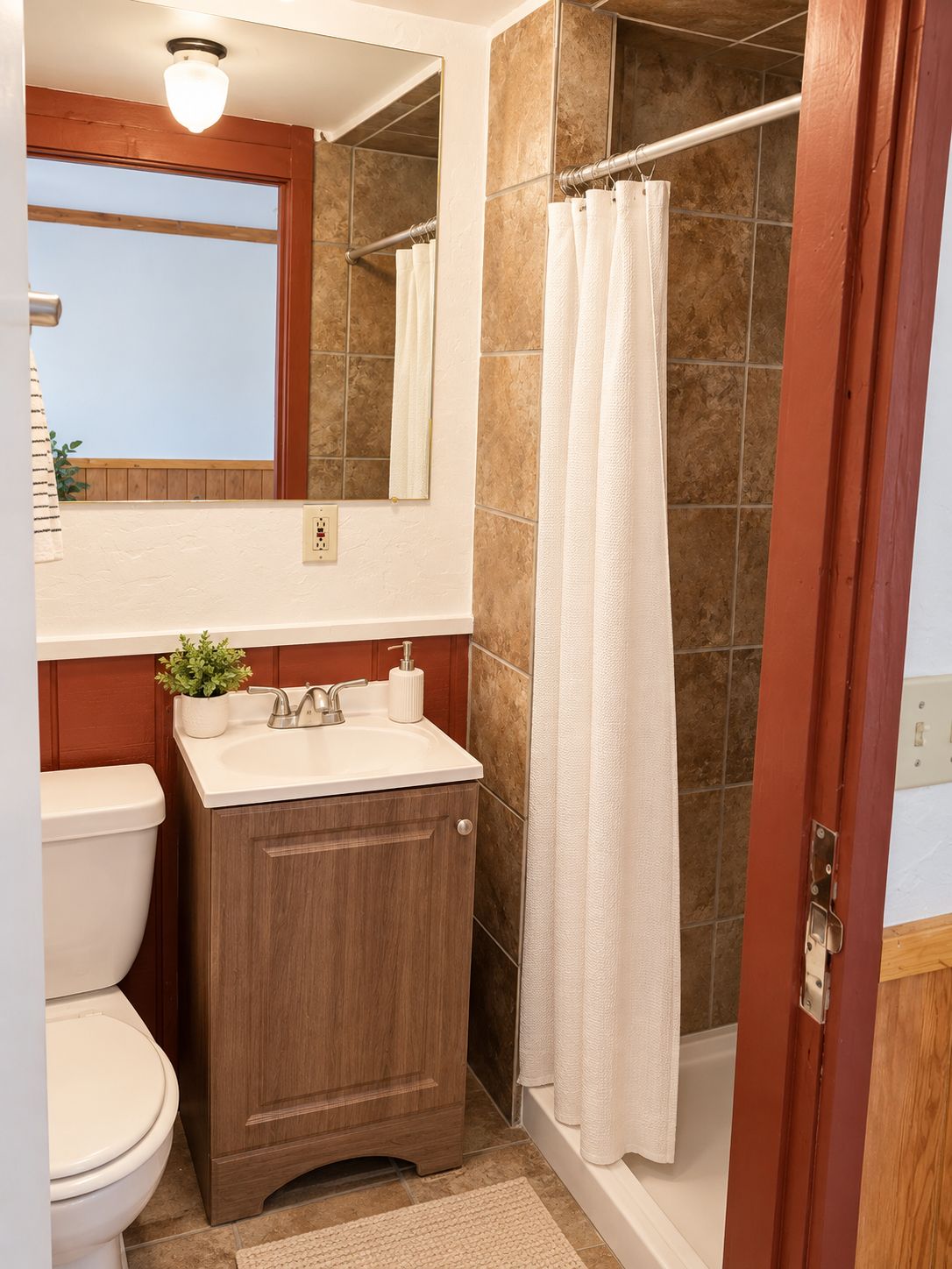 A bathroom with a toilet, sink, and shower area.