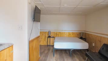 Une chambre de taille modeste, comprenant un lit, un téléviseur fixé au mur et une petite table.