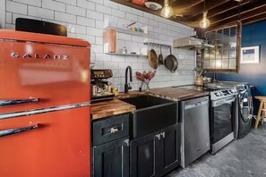 Eine Küche mit einem roten Galanz-Kühlschrank, einer Holz Arbeitsplatte, einem Spülbecken und einem Geschirrspüler.