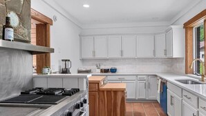 A kitchen with white cabinets, a central island, a stove, and a sink.