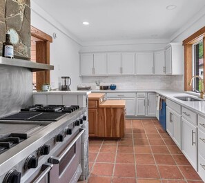 A kitchen with white cabinets, a central island, a stove, and a sink.