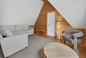 Een moderne loft slaapkamer met schuine wanden, een bank, een kleine tafel, een stoel en een bed.