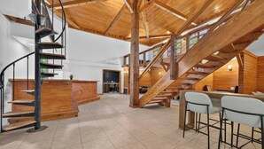 A spacious interior with a wooden staircase, a bar area, and a dining space.