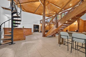 A spacious interior with a wooden staircase, a bar area, and a dining space.