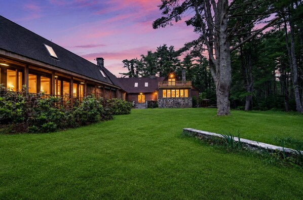 A two-story house with a well-maintained lawn and a large tree in the foreground.