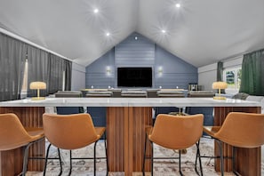 Een moderne keuken met een centraal eiland, een bar en een flatscreen televisie.