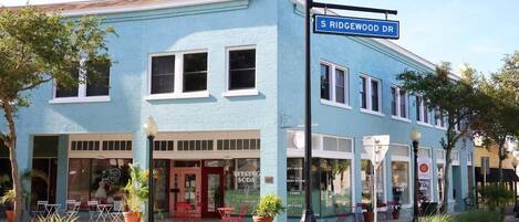 A two-story building with a blue facade, a street sign reading 'S RIDGEWOOD DR', and storefronts including a soda shop.