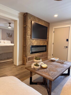 A modern living room with a fireplace, a television mounted on the wall, and a dining table with decorative items. - Newly renovated 2-bedroom condo in lovely Hilton Head Island with AC (Hilton Head Island)