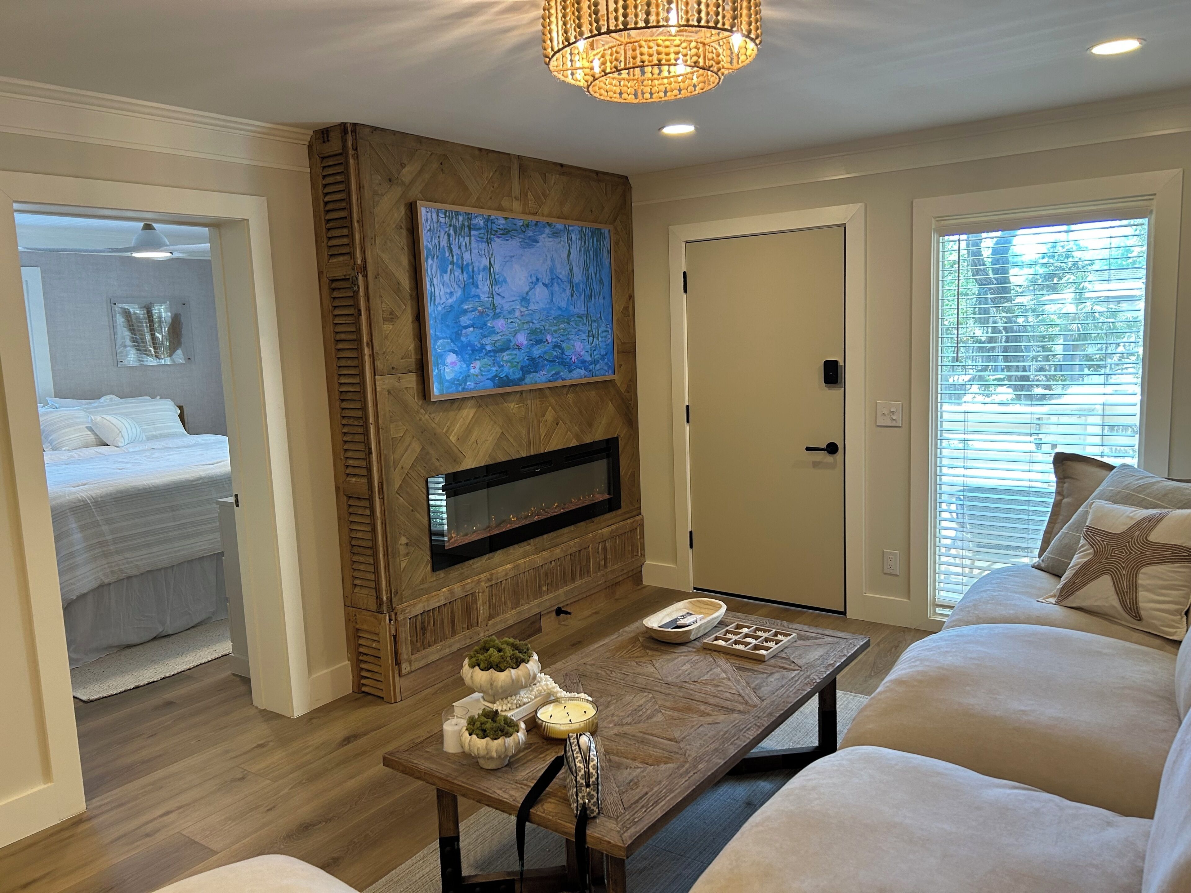 A modern living room with a fireplace, a painting, a dining table with decorative items, and a sofa.