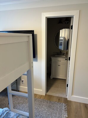 Een slaapkamer met een bed, een witte kledingkast, en een badkamer zichtbaar door een geopende deur.