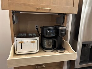 Een aanrecht met een broodrooster, koffiezetapparaat en een Keurig koffiepadapparaat.