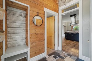 Un pasillo con pared de madera, un espejo y una puerta que da a una zona de cocina.