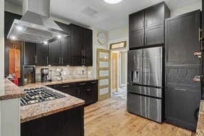 Una cocina moderna con armarios oscuros, un refrigerador de acero inoxidable y una estufa a gas empotrada.