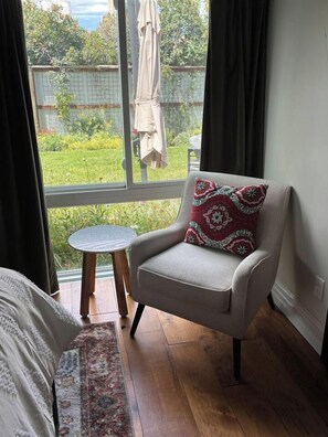 A room with a window, a chair with a patterned cushion, a small round table, and a patterned rug. - The Historic Sugar Mill House with Hot Tub (Loveland)