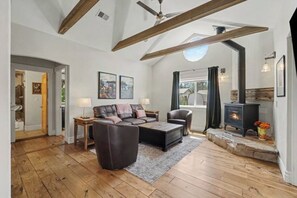 A spacious living room with a fireplace, wooden beams, and a stone fireplace surround. - The Historic Sugar Mill House with Hot Tub (Loveland)