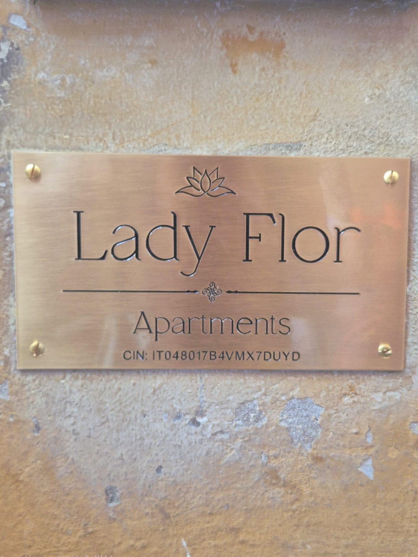 Eine Metallplatte mit dem Schriftzug 'Lady Flor Apartments' und einer CIN-Nummer.