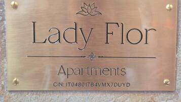 Eine Metallplatte mit dem Schriftzug 'Lady Flor Apartments' und einer CIN-Nummer.