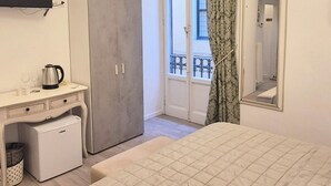 A hotel room with a bed, a desk with a kettle, a wardrobe, a television, and a balcony with a railing. - Lady Flor B&B (Firenze)