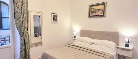 Ein Schlafzimmer mit Bett, Bank, Chandelier, Nachttisch und einem gerahmten Bild an der Wand.