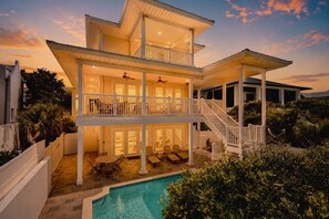 Ein zweistöckiges Haus mit Pool, mehreren Balkonen und Sitzgelegenheiten im Freien.