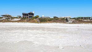 Una spiaggia con impronte, una scalinata che conduce a un edificio e un cielo sereno.