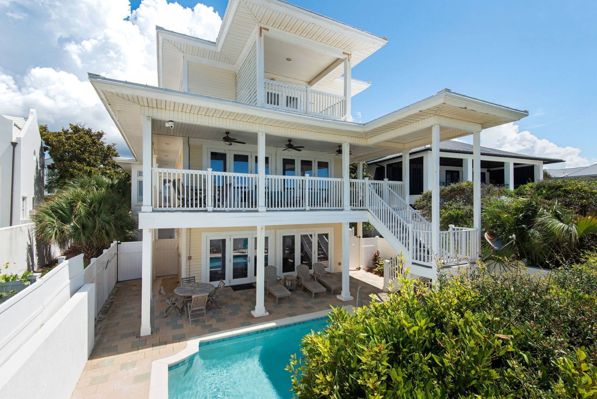 A two-story house with a pool, outdoor furniture, and a covered patio area.
