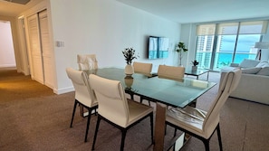 Ein modernes Wohnzimmer mit einem Glastisch, weißen Sofas und Blick auf den Ozean.