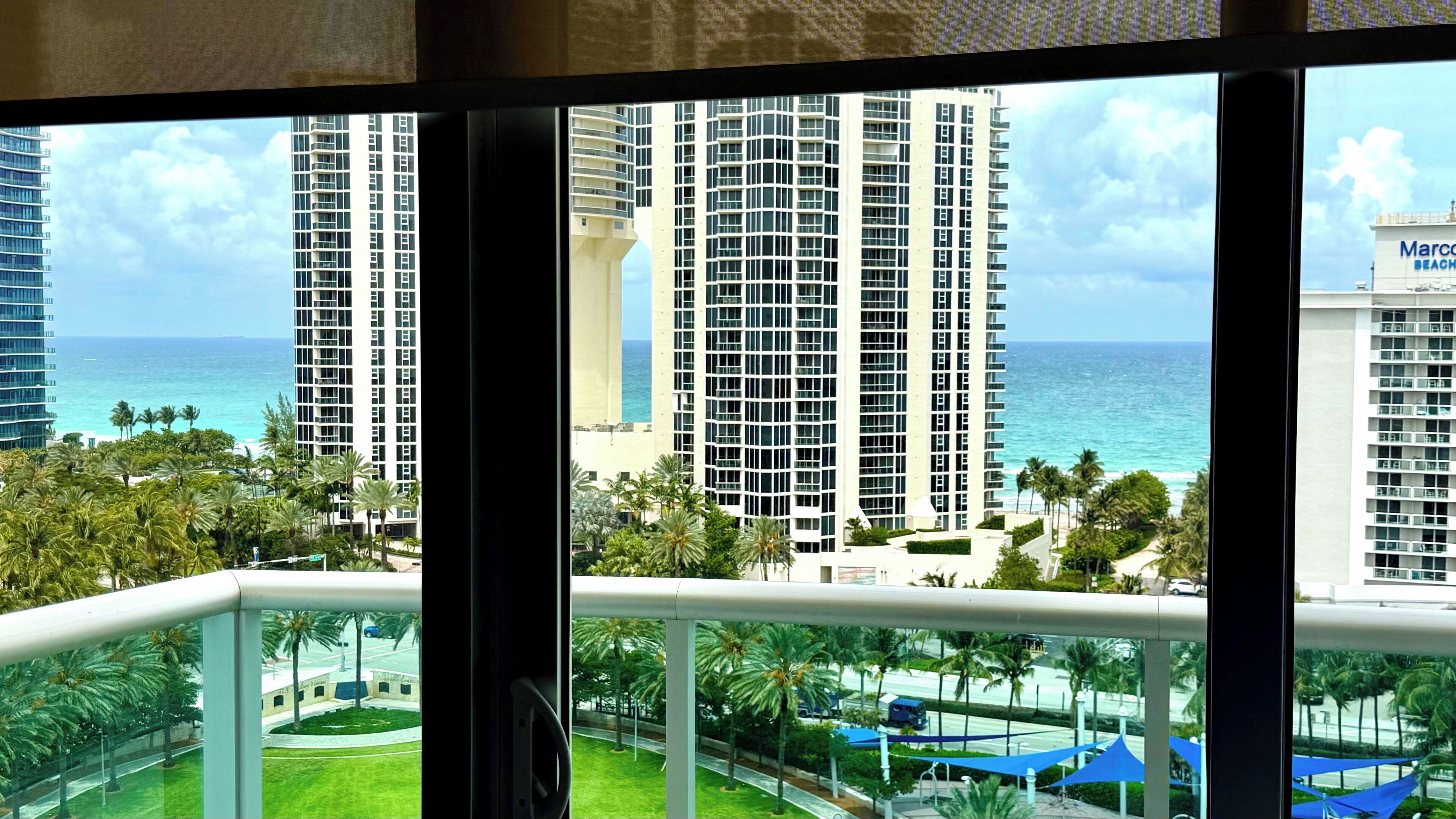 A high-rise building with a view of the ocean and palm trees.
