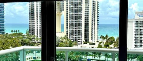 A high-rise building with a view of the ocean and palm trees.