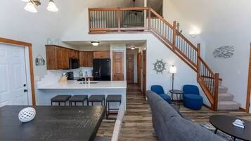 Uma sala de estar espaçosa com cozinha, mesa de jantar e escada para o andar superior.
