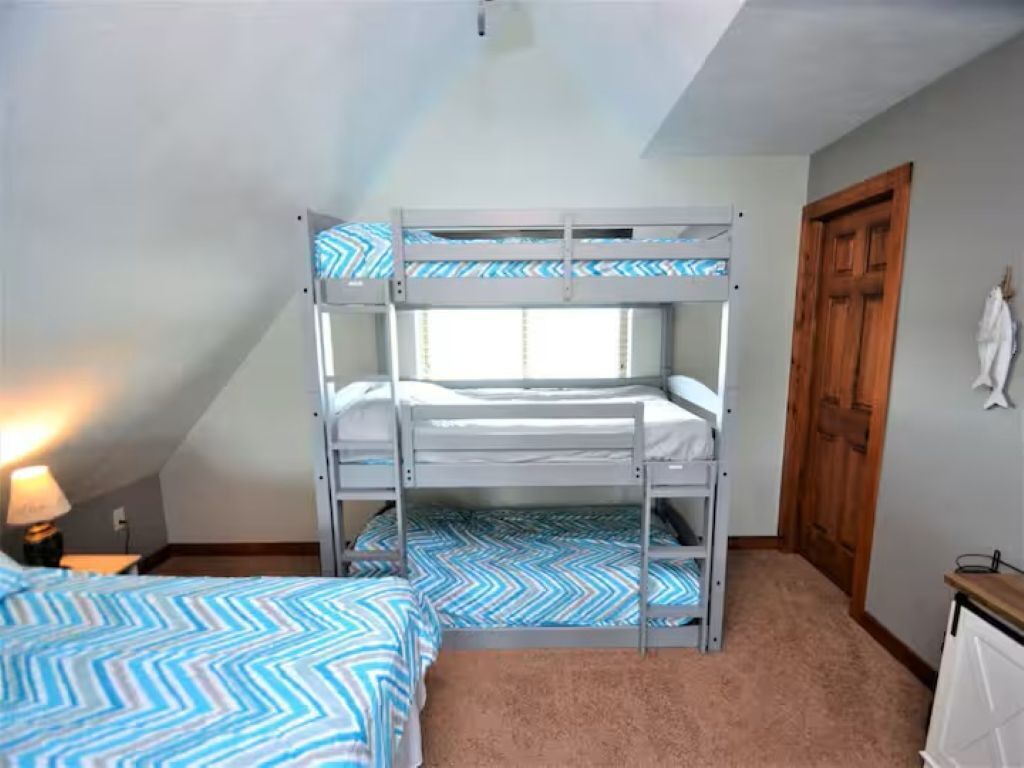 A bunk bed room with a window, a door, and a lamp.