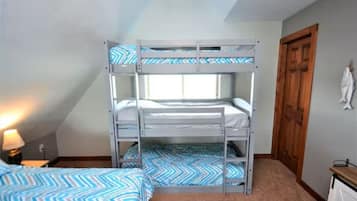 A bunk bed room with a window, a door, and a lamp.