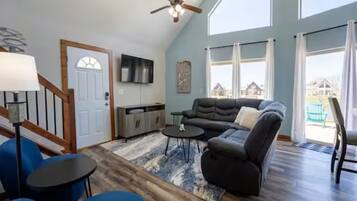 A spacious living room with a sectional sofa, a ceiling fan, and a large window offering a view of the outside.
