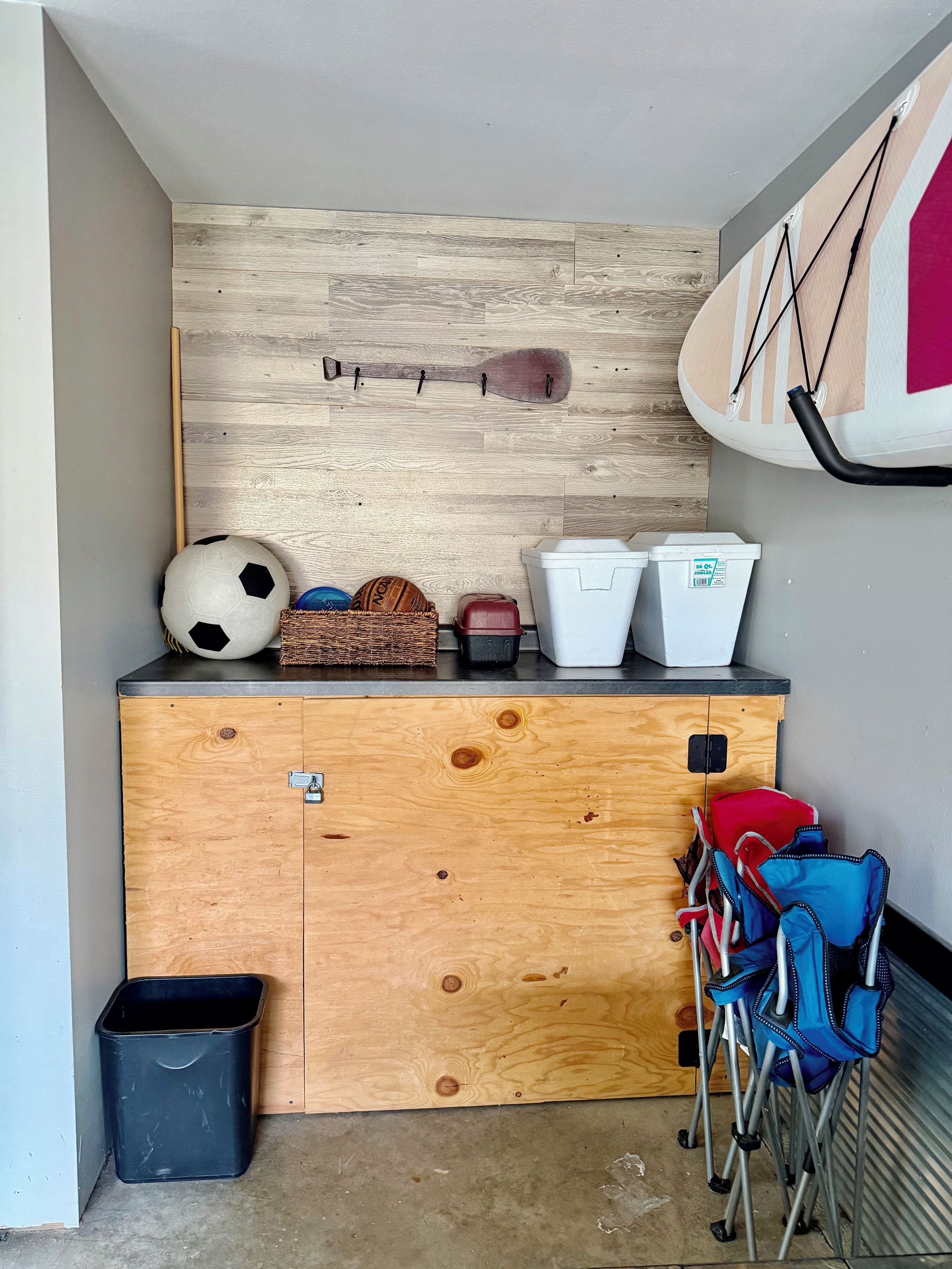 Habitación pequeña con un armario de madera, una tabla de surf y varios equipos deportivos.