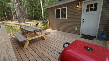 A wooden deck with a picnic table and a red grill.