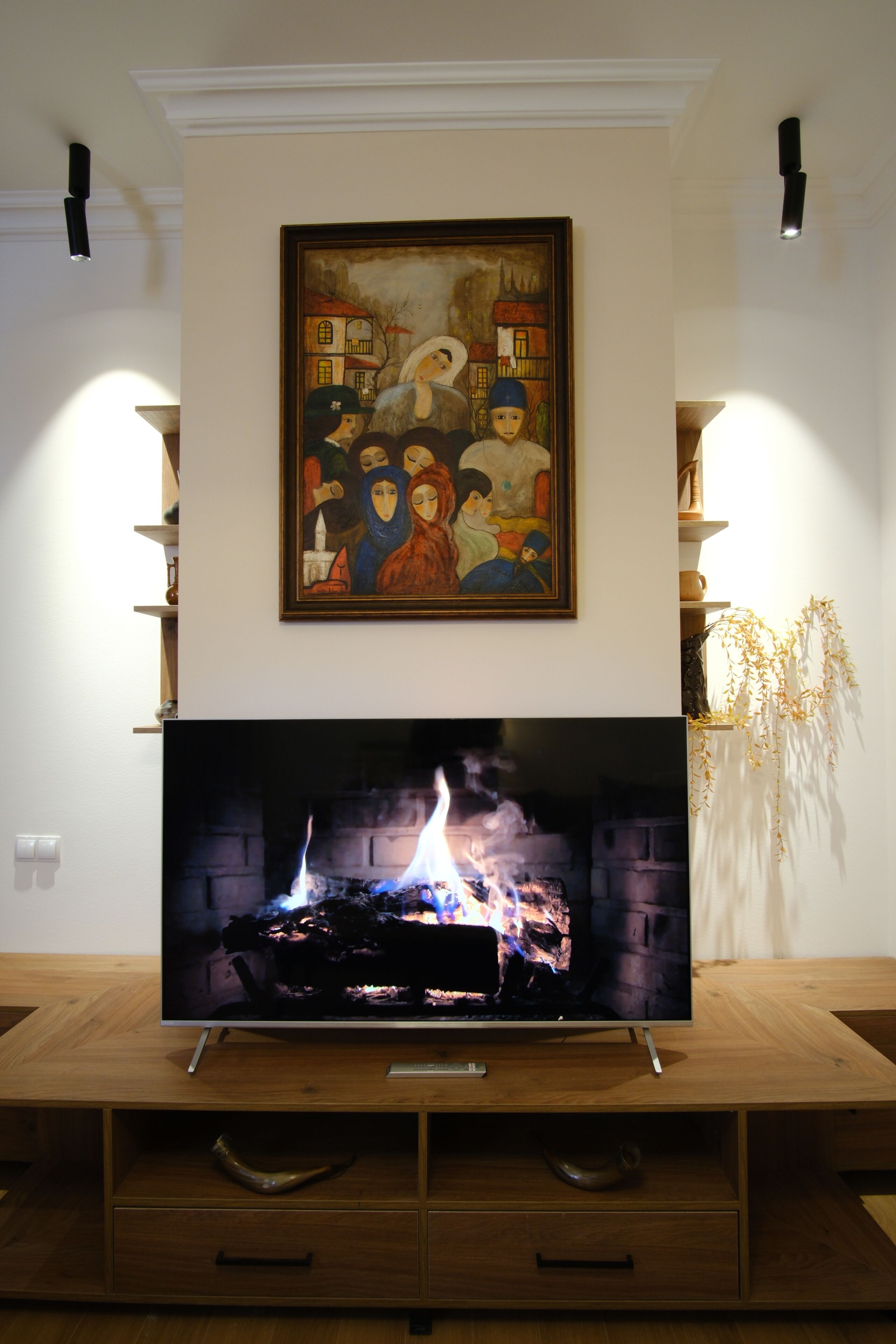 A flat-screen TV on a wooden stand with a fireplace below it.