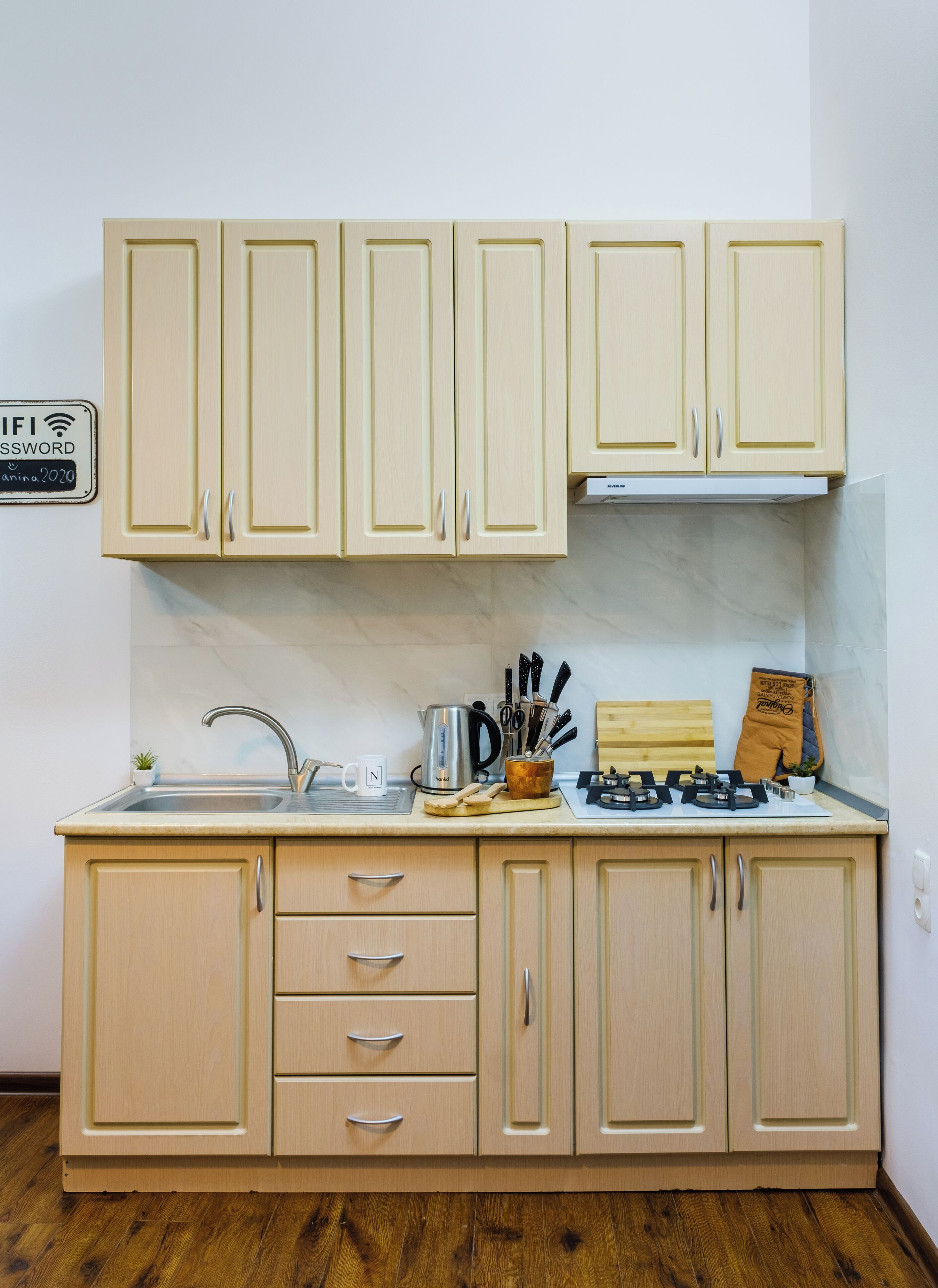 A kitchen with light wooden cabinets, a stainless steel sink, and a gas stove.