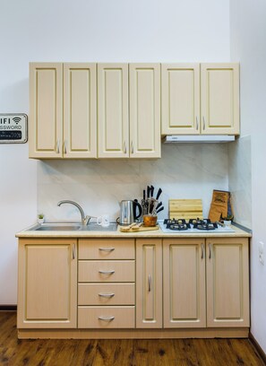 A kitchen with light wooden cabinets, a stainless steel sink, and a gas stove.