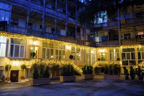 A multi-story building with balconies, a covered walkway, and potted plants.