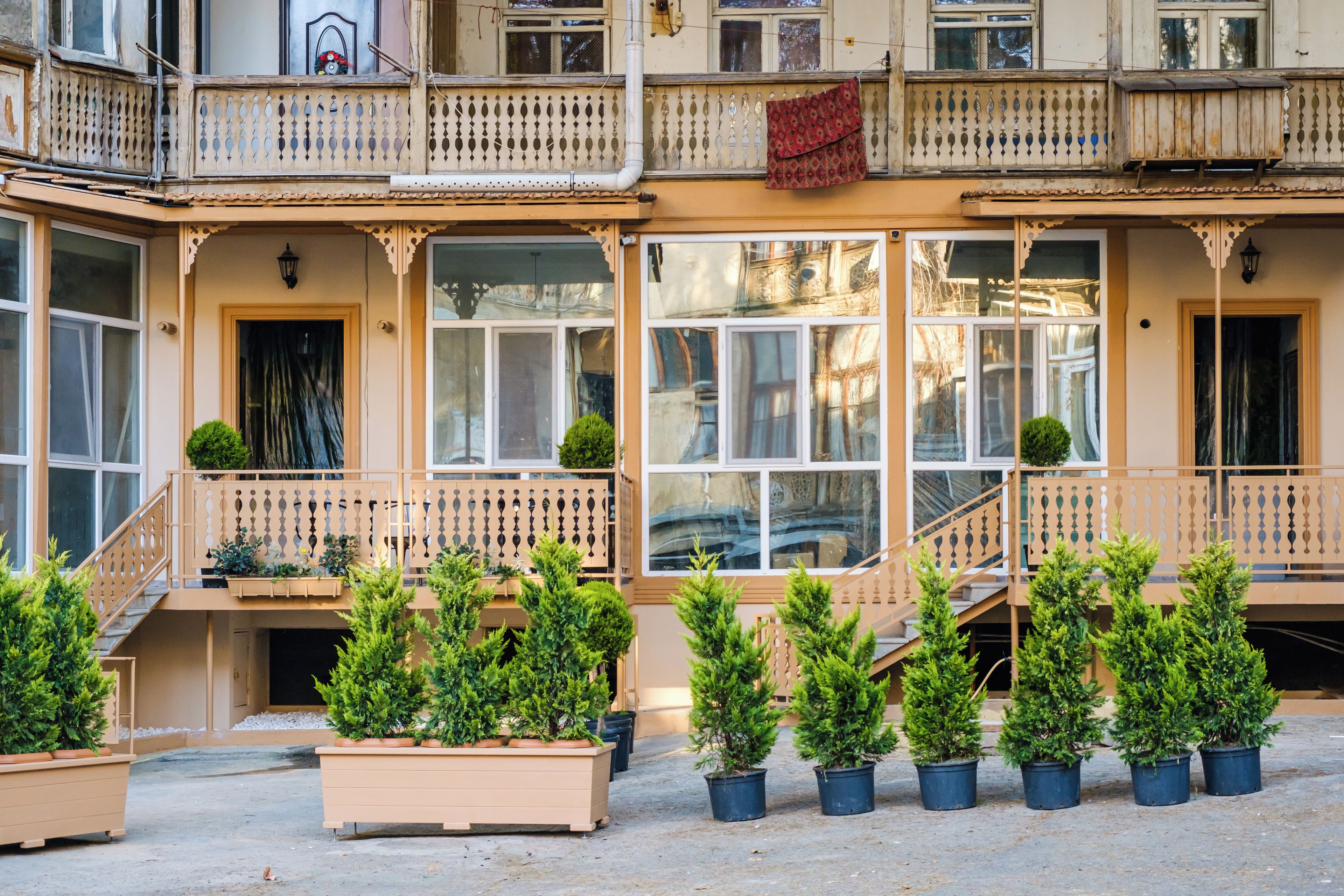 A building with multiple balconies, large windows, and potted plants.