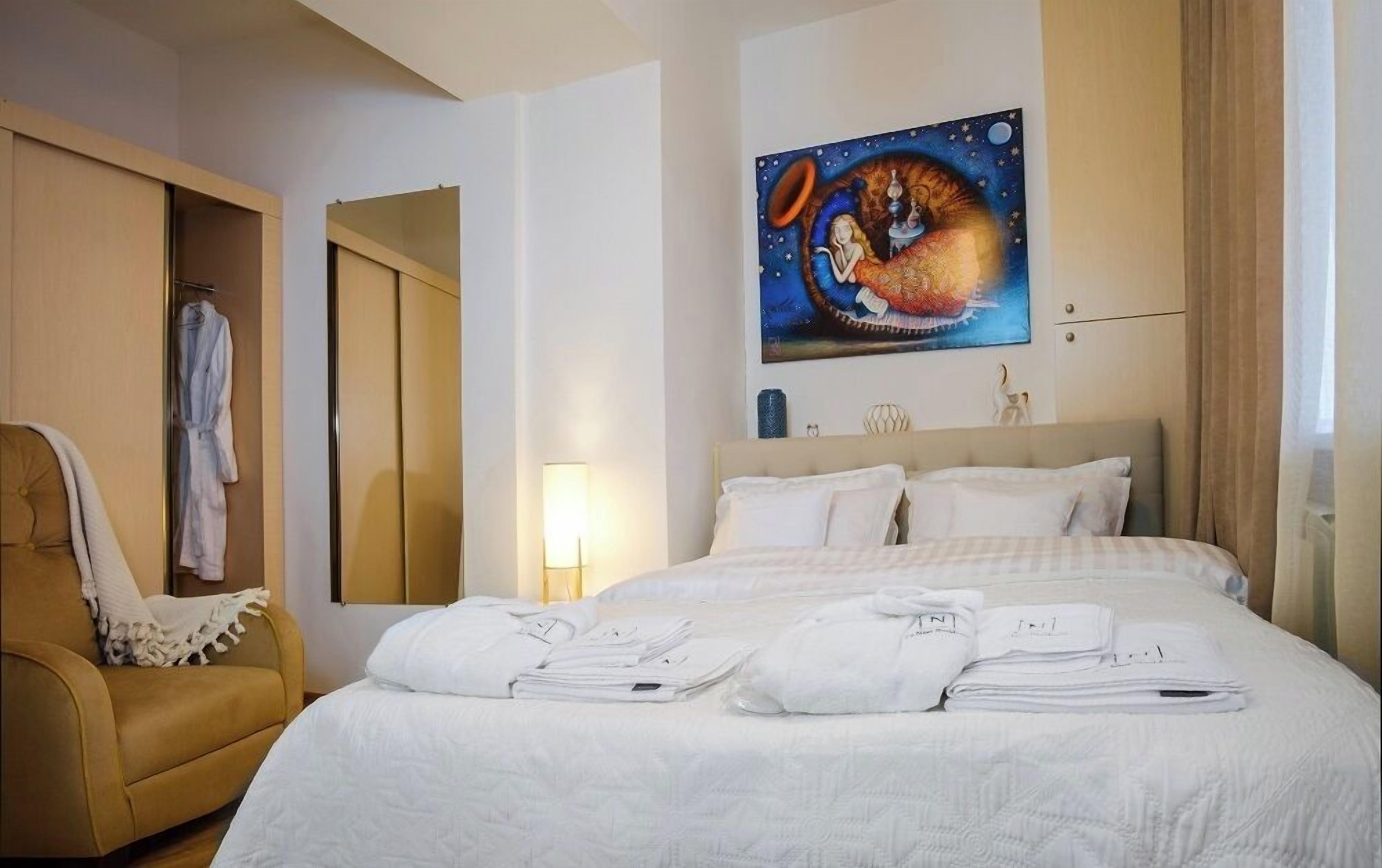 Una habitación de hotel con cama, una silla, un cuadro y un armario.